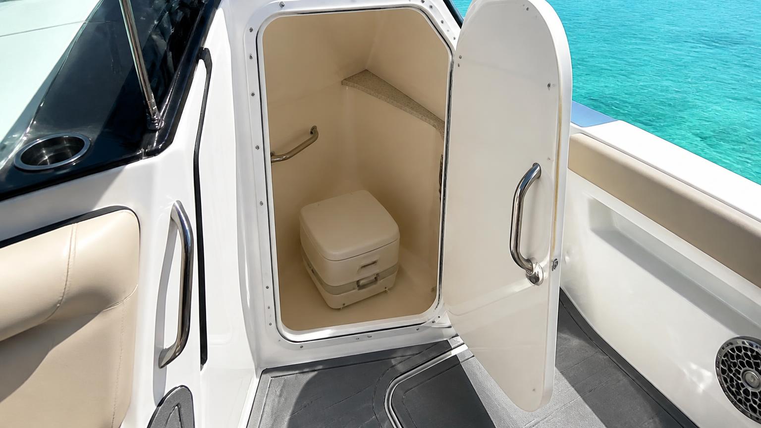 Open console door of a Bowrider Amazing Photo by www.BOWRIDER-BOATS.com — Open console door of a bowrider revealing the compact enclosed head compartment with a portable marine toilet inside. Images Created by www.Bowrider-Boats.com